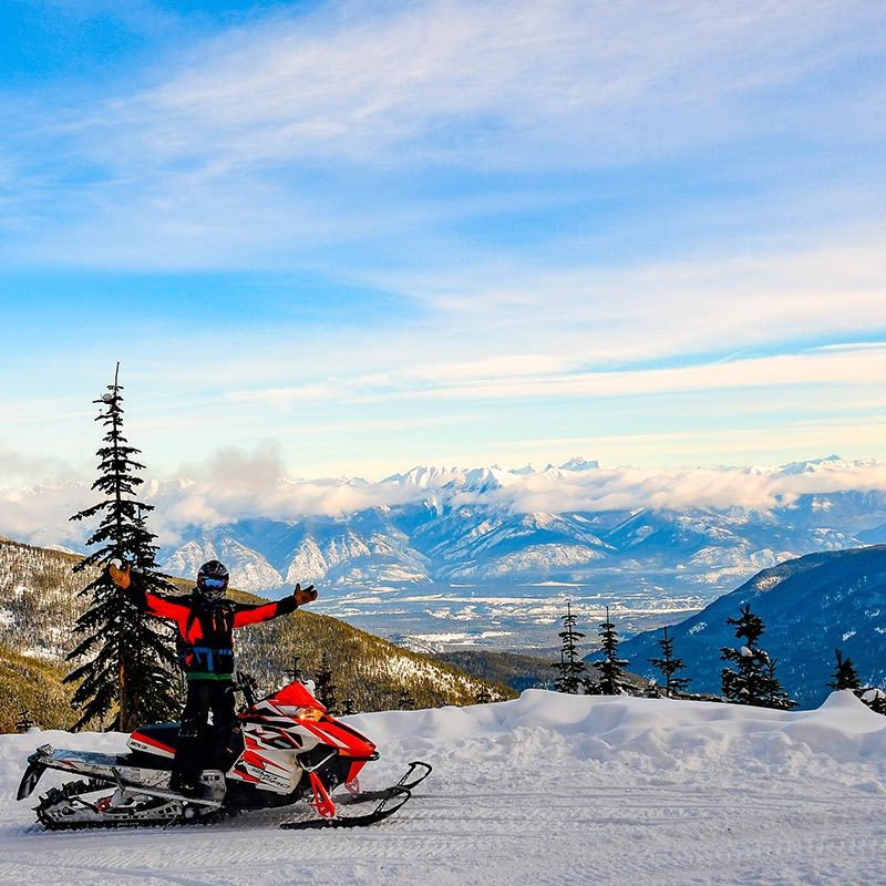 Man op sneeuwscooter met uitzicht op bergpanorama