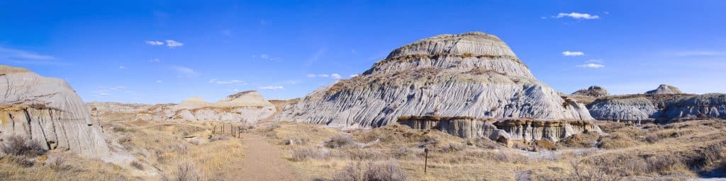 Panorama van de badlands in Dinosaur Provincial Park met geërodeerde heuvels, rotslagen en droog steppegras.