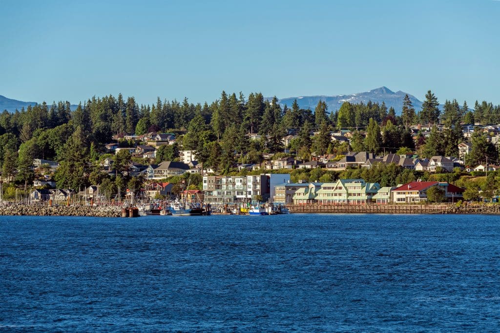 Uitzicht op de waterfront van Campbell River met woningen, bomen en vissersboten langs de kust.