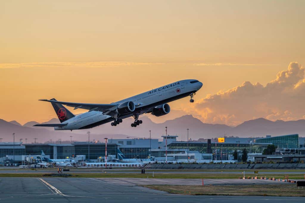 Air Canada-vliegtuig dat opstijgt vanaf Vancouver International Airport bij zonsondergang.