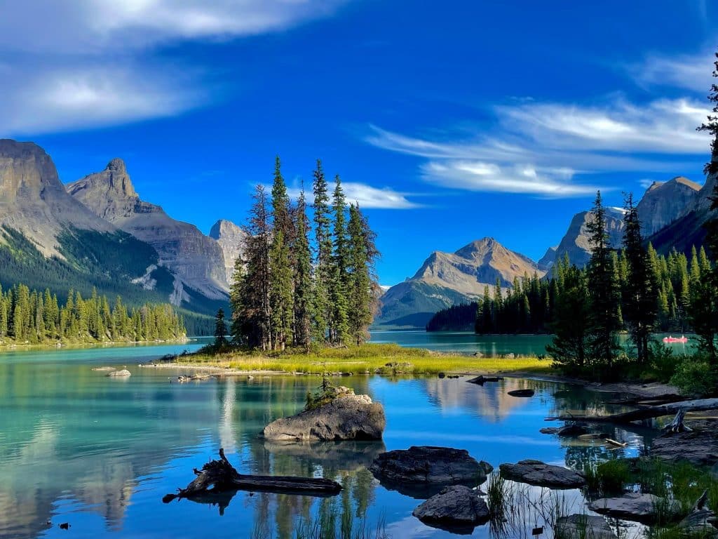 Blauw bergmeer met een klein eiland vol naaldbomen, omringd door hoge bergen in Jasper National Park.
