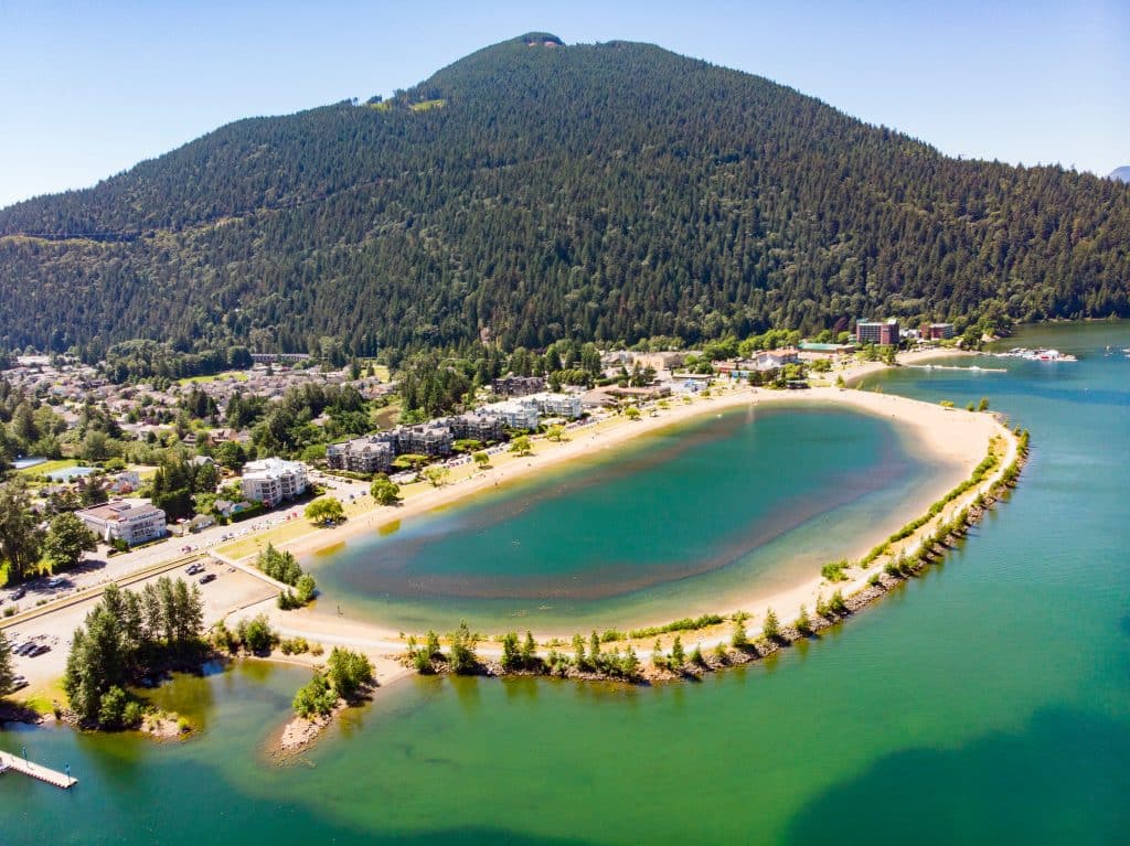 Luchtfoto van White Pine Beach aan Sasamat Lake, met een bosrijke berg op de achtergrond.
