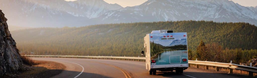 Camper op kronkelende bergweg in Canada met bergen bij zonsondergang