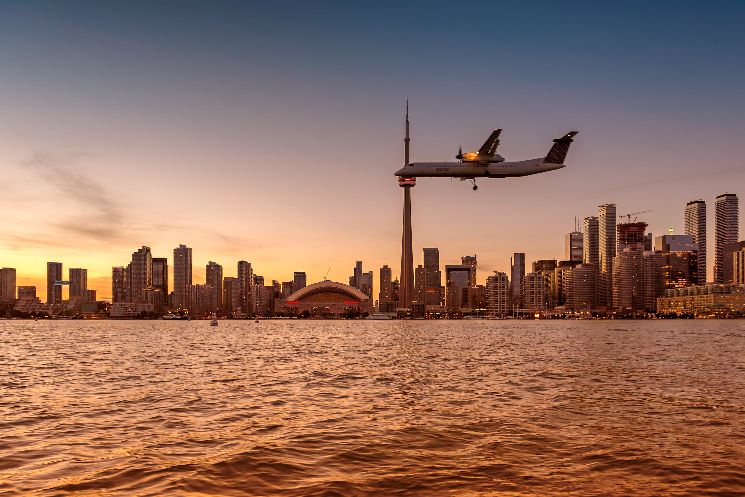 Toronto skyline met CN Tower en vliegtuig bij zonsondergang