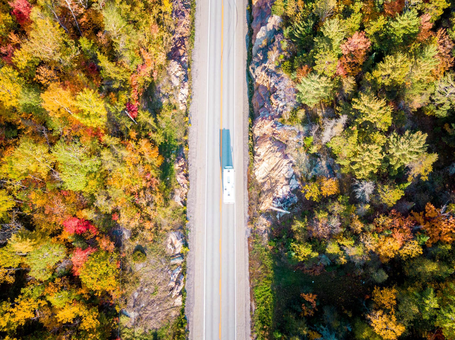 Camper op weg door herfstbos in Ontario Canada vanuit lucht