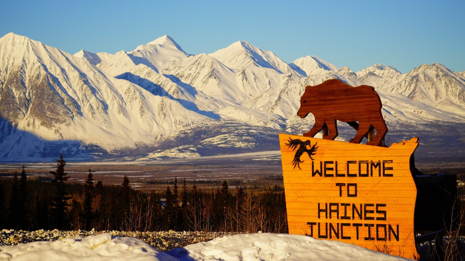 Yukon YT Haines Junction welkomstbord met besneeuwde bergen