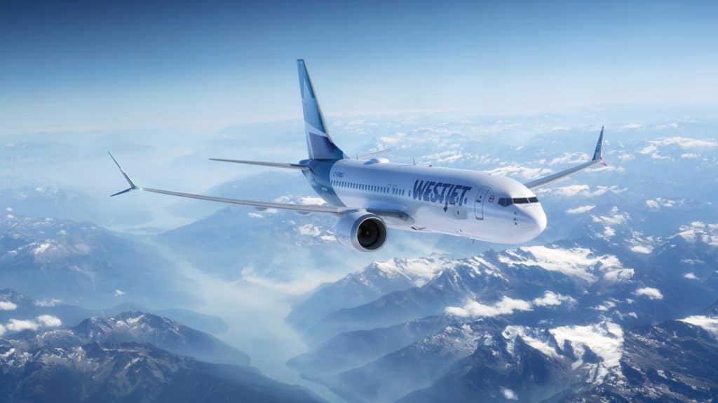 WestJet vliegtuig vliegt boven besneeuwde bergen en meren in Canada