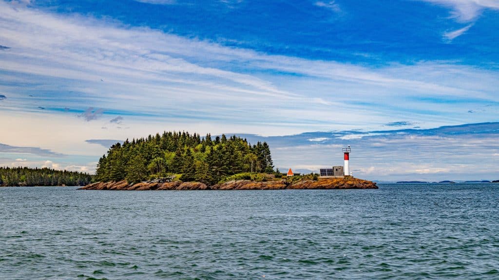 Klein eiland met vuurtoren bij St. Andrews-by-the-Sea in zee