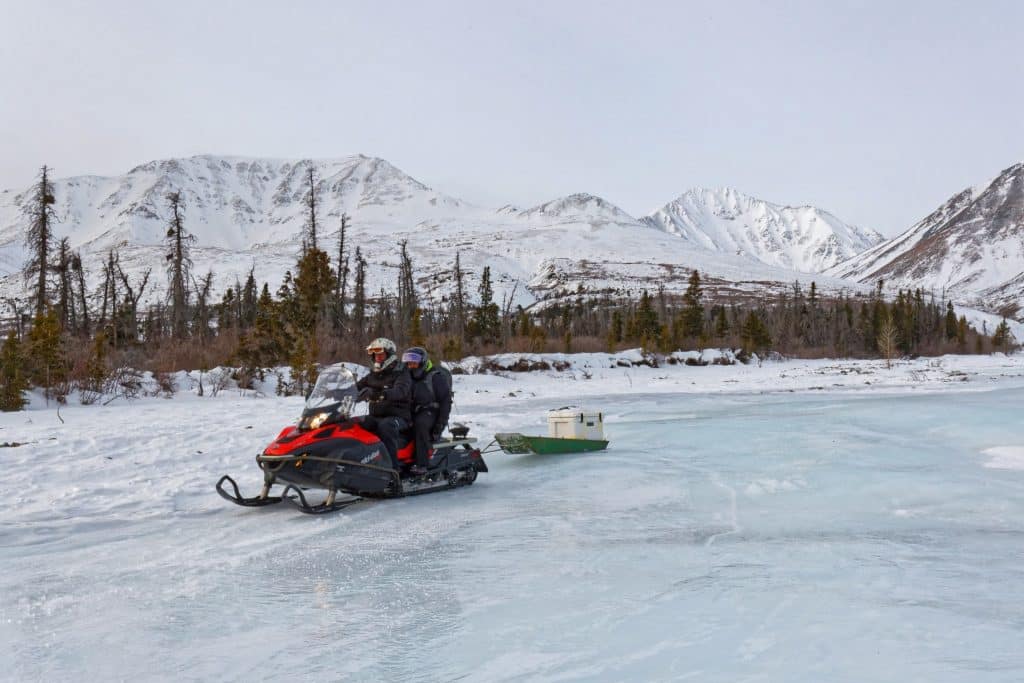 Yukon YT Yukon Winterlandschap sneeuwscooter op bevroren rivier met bergen